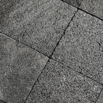 Gray stone tiles form a grid pattern, displaying a rough texture, aligned neatly in an outdoor setting.