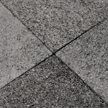 Gray stone tiles form a textured, interlocking pattern on a flat surface, creating a uniform, durable floor.