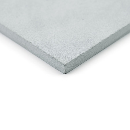 A smooth, gray stone tile sits angled slightly upward, highlighting its textured, precise edge against a plain, white background