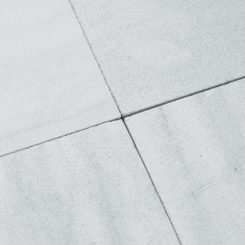 Quatre carreaux de pierre gris clair se rejoignent aux coins, formant un motif en croix. La surface apparaît lisse et légèrement