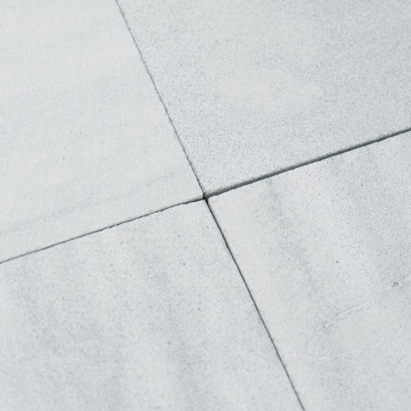 Quatre carreaux de pierre gris clair se rejoignent aux coins, formant un motif en croix. La surface apparaît lisse et légèrement