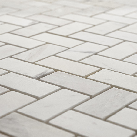 Rectangular stone tiles form a herringbone pattern, creating a uniform surface with light gray and white tones.