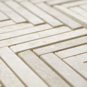 Rectangular stone tiles form a geometric, interlocking pattern on a flat surface, creating a textured, light-colored mosaic.