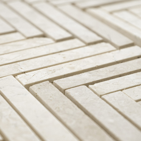 Rectangular stone tiles form a geometric, interlocking pattern on a flat surface, creating a textured, light-colored mosaic.