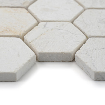 Hexagonal stone tiles lie closely together, displaying a textured, off-white surface in a bright, minimal space.