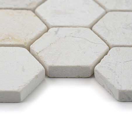 Hexagonal stone tiles lie closely together, displaying a textured, off-white surface in a bright, minimal space.