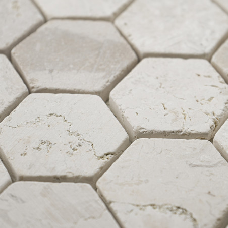 Hexagonal stone tiles form a textured pattern, with rough white surfaces and subtle gray veins, closely arranged.