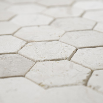 Hexagonal stone tiles interlock closely, creating a textured, seamless white surface in a crisp, geometric pattern.