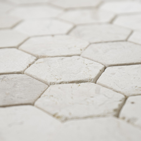 Hexagonal stone tiles interlock closely, creating a textured, seamless white surface in a crisp, geometric pattern.