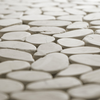 Smooth, oval stone tiles fit tightly together, creating a seamless surface in a softly lit environment.