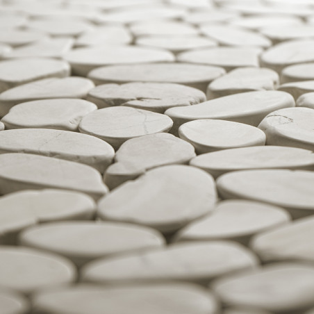 Smooth, oval stone tiles fit tightly together, creating a seamless surface in a softly lit environment.