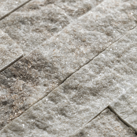 Rough, textured stone tiles lie stacked horizontally, showcasing a natural, earthy blend of light and dark tones.