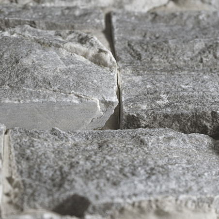 Gray stone tiles arranged side by side, forming a textured surface in a natural, rugged setting.