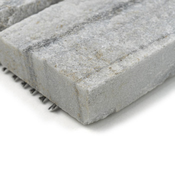 Rough gray stone tile displays speckled texture, resting on a white surface, showcasing layered patterns on edges.