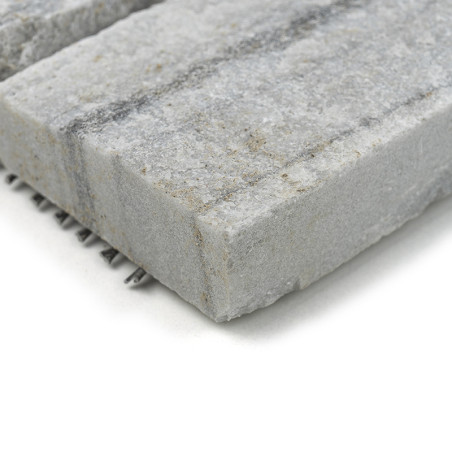 Rough gray stone tile displays speckled texture, resting on a white surface, showcasing layered patterns on edges.