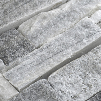 Des carreaux de pierre rectangulaires sont assemblés, mettant en valeur des textures brutes et variées et des nuances de gris, c