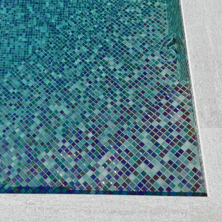Blue and green mosaic tiles create an intricate pattern, lining the bottom of a rectangular swimming pool.