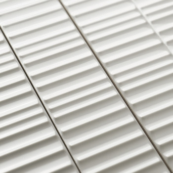 Les carreaux de céramique blanche présentent des crêtes linéaires surélevées, disposées parallèlement, créant un motif texturé. 