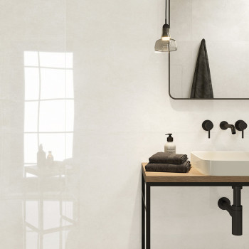 Een witte badkamer is voorzien van een minimalistische wastafel op een houten aanrecht, met zwarte armaturen, een hanglamp en ee