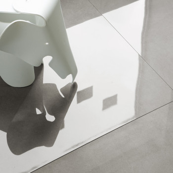 Un objeto de plástico blanco con forma de elefante proyecta una sombra sobre azulejos de color gris claro y brillantes, reflejan
