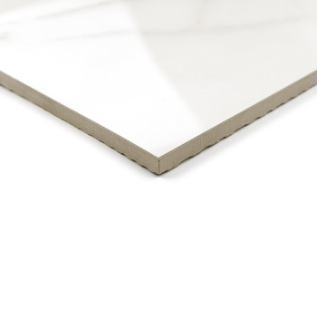 Un azulejo de cerámica blanca con acabado brillante y borde biselado se encuentra sobre un fondo blanco, reflejando la luz natur