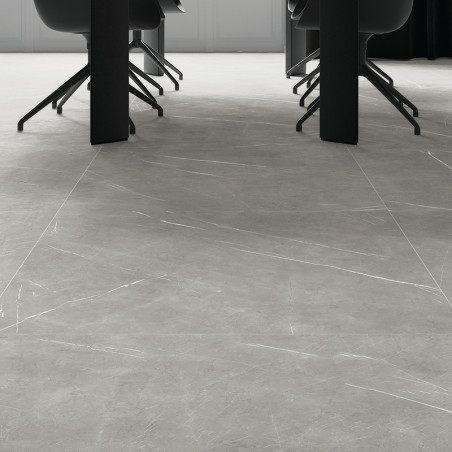 Ladrilhos de mármore cinza cobrem um piso elegante e moderno sob cadeiras escuras e uma mesa longa, criando um ambiente elegante