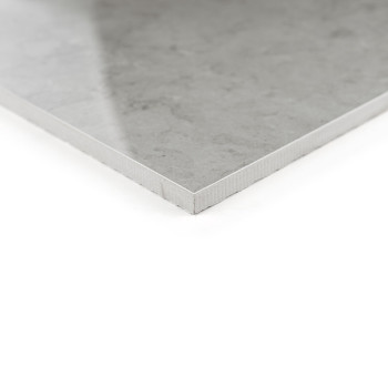 Un carreau de céramique lisse et gris en position de coin, mettant en valeur sa surface polie et son profil fin, repose sur un f