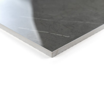 Un carreau gris foncé poli avec des motifs veinés subtils repose sur une surface blanche, reflétant une lumière douce dans un dé