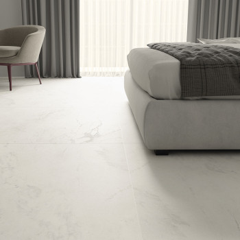 El piso de mármol blanco se extiende a lo largo de un dormitorio moderno, con una silla y una cama acolchadas, con cortinas gris