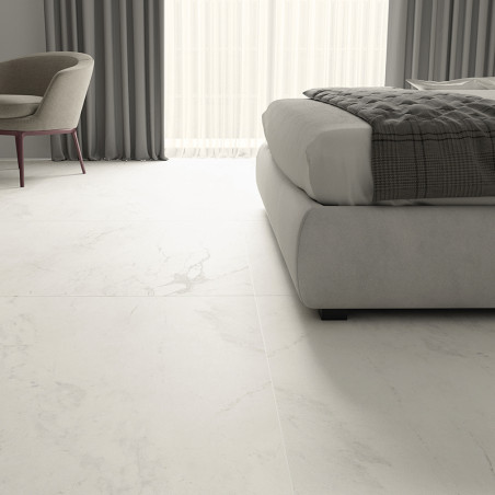 El piso de mármol blanco se extiende a lo largo de un dormitorio moderno, con una silla y una cama acolchadas, con cortinas gris