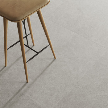 Un taburete de madera se encuentra sobre un suelo de azulejos de color gris claro, y las patas del taburete proyectan sombras, l