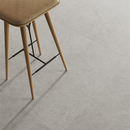 Un taburete de madera se encuentra sobre un suelo de azulejos de color gris claro, y las patas del taburete proyectan sombras, l