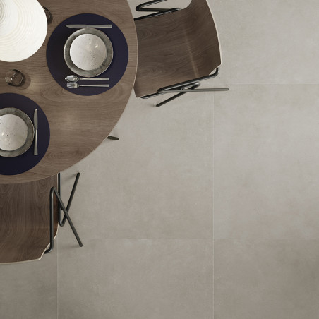 Una mesa redonda de madera con manteles individuales, platos y cubiertos oscuros. rodeado de sillas curvas sobre un suelo de azu