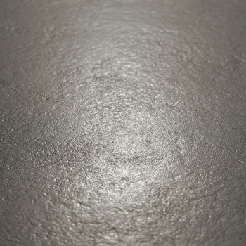 La superficie del azulejo metálico refleja la luz suavemente, mostrando una textura ligeramente desigual en un ambiente neutro y