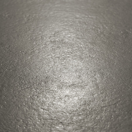 A superfície metálica do ladrilho reflete a luz suavemente, exibindo uma textura ligeiramente irregular em um ambiente neutro e 