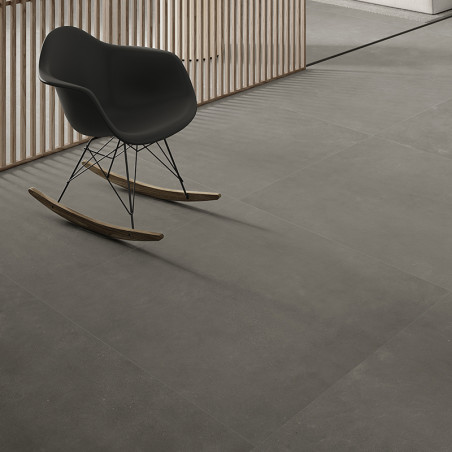 Una elegante mecedora negra descansa sobre grandes y suaves azulejos grises en un interior moderno con tabiques de listones de m
