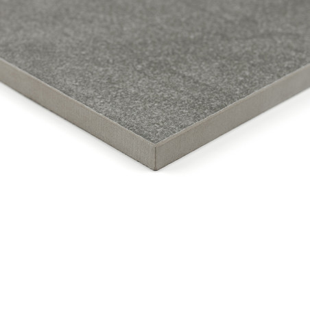Un azulejo cerámico cuadrada, de color gris y con una superficie lisa, se apoya sobre un fondo blanco, destacando su espesor y s