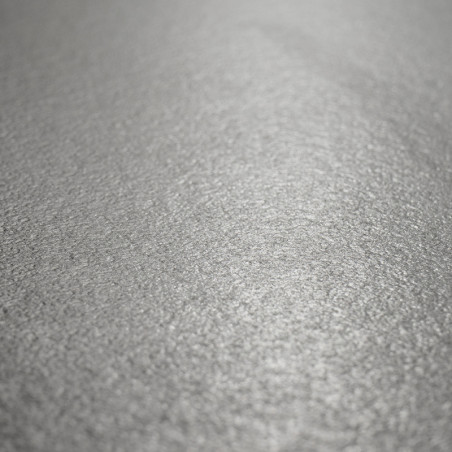 Una superficie de mosaico texturizada de color gris claro refleja la luz sutilmente, creando un efecto brillante en su patrón un