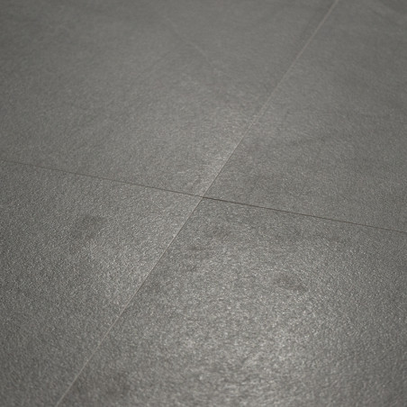 Un azulejo de color gris mate yace plana, cruzada por sutiles líneas de lechada, creando una superficie suave y uniforme en un e