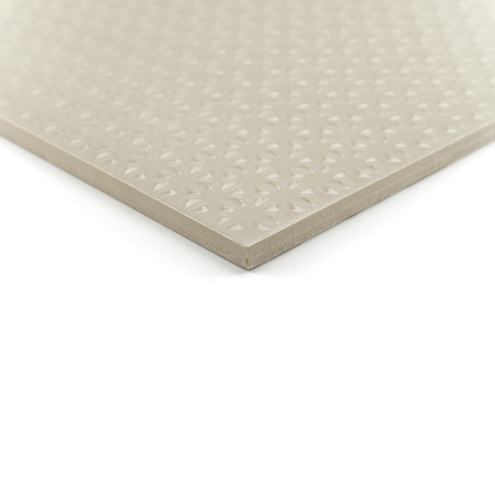 Un carreau carré beige repose sur un fond blanc, affichant un motif géométrique en relief sur sa surface lisse.