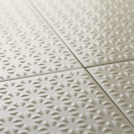 Les carreaux de céramique texturés forment un motif répétitif de formes rayonnantes de soleil dans une couleur beige douce, soig