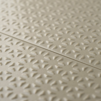 Les carreaux beiges présentent un motif floral en relief répétitif, créant de la texture et de la profondeur. Les carreaux s’ali