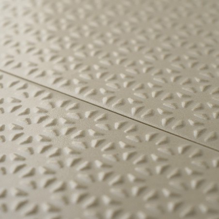 Les carreaux beiges présentent un motif floral en relief répétitif, créant de la texture et de la profondeur. Les carreaux s’ali