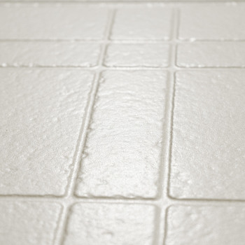 Los azulejos rectangulares de color beige claro texturizados están dispuestos en un patrón de cuadrícula, creando una superficie