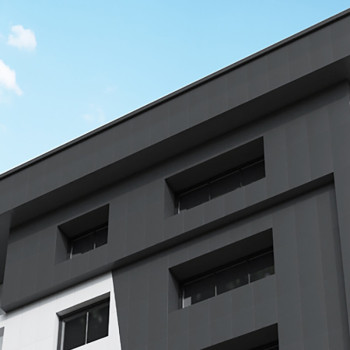 Een modern gebouw heeft donkere en lichte rechthoekige panelen en ramen, afgezet tegen een helderblauwe lucht met minimale bewol