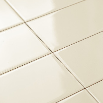 Les carreaux de céramique de couleur crème sont disposés selon un motif en grille, réfléchissant doucement la lumière sur un sol