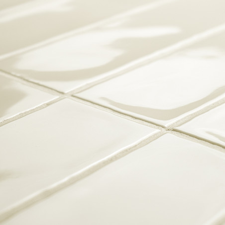 Glanzende witte rechthoekige tegels vormen een rasterpatroon en reflecteren het licht in een ruime kamer, met licht zichtbare vo