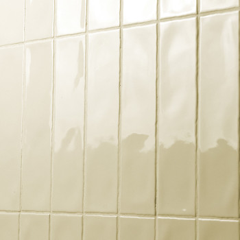 Rechthoekige, glanzende tegels worden in een rasterpatroon op een muur aangebracht en reflecteren het licht in een badkamer of k