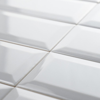 White, glossy rectangular tiles are neatly arranged in a grid pattern, creating a reflective surface. The subtle beveling adds d