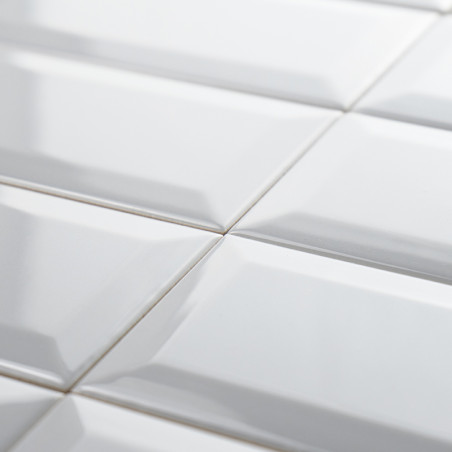 White, glossy rectangular tiles are neatly arranged in a grid pattern, creating a reflective surface. The subtle beveling adds d